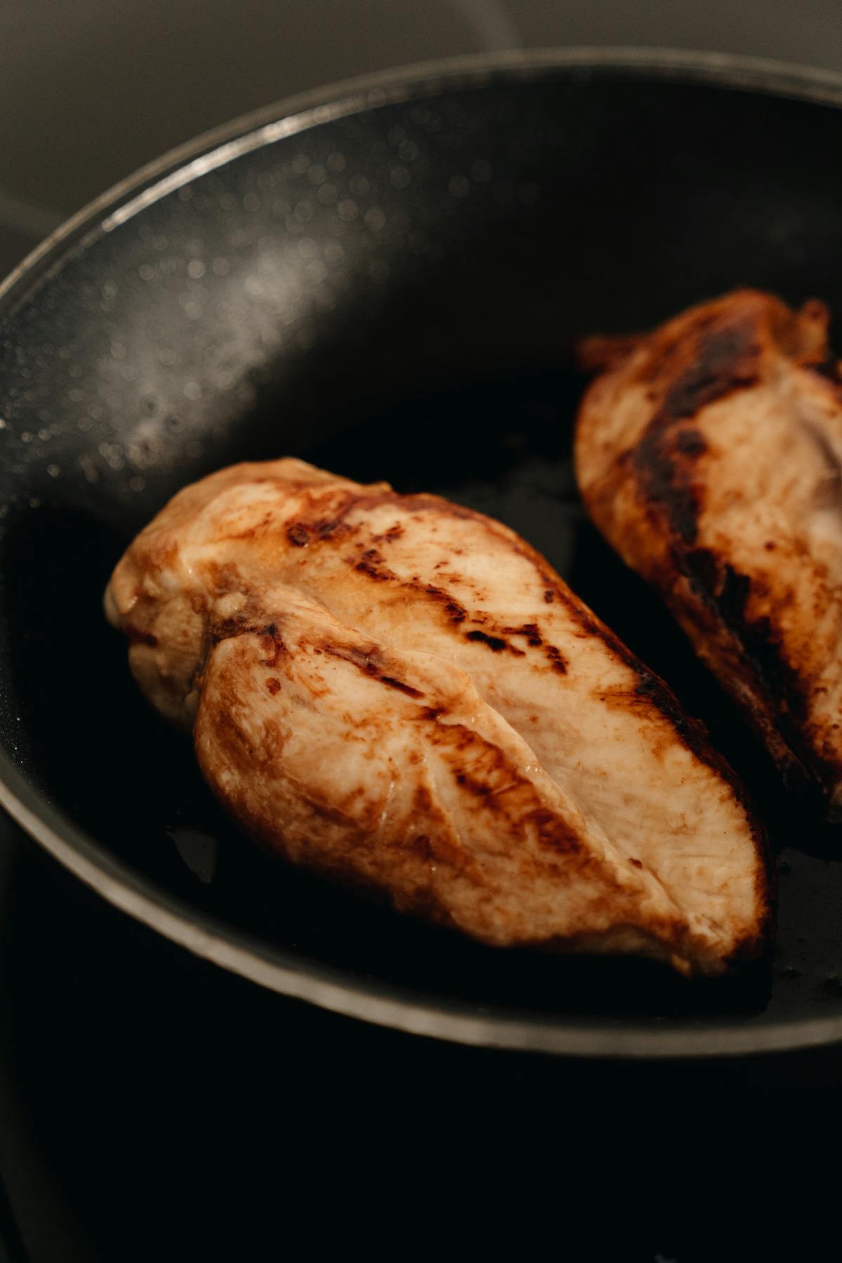 Chicken cooking in a hot skillet on the stovetop, illustrating USDA-approved cook-from-frozen technique for weeknight dinners